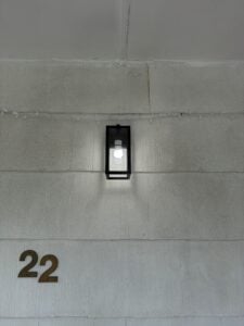 Black outdoor wall light installed beside a front door by Spartan Home Pros